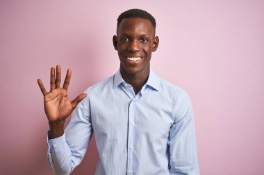 Izole pembe arka plan üzerinde duran mavi zarif gömlek giyen Afrikalı Amerikalı adam gösteren ve emin ve mutlu gülümserken parmakları ile beş işaret.