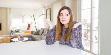 Evde güzel genç kadın silah ve elleri kaldırdı ile habersiz ve karışık ifade. Şüphe kavramı.