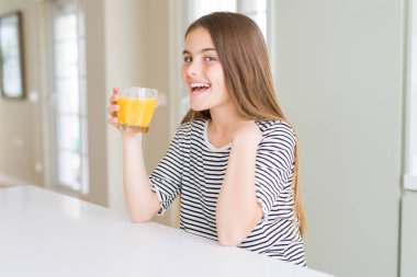 Güzel genç kız çocuk kendini işaret sürpriz yüzü ile taze portakal suyu bir bardak içme