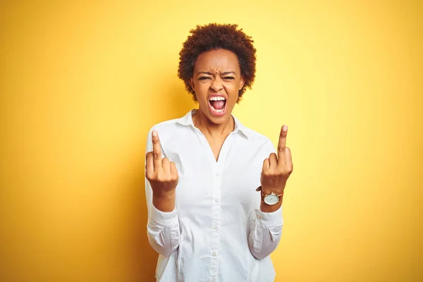 African american business woman over isolated yellow background Showing middle finger doing fuck you bad expression, provocation and rude attitude. Screaming excited