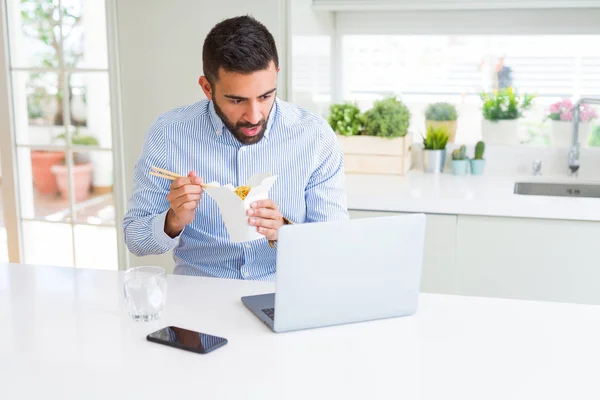 Człowiek biznesowy jedząc Azjatyckie jedzenie z dostawą podczas pracy przy użyciu — Zdjęcie stockowe