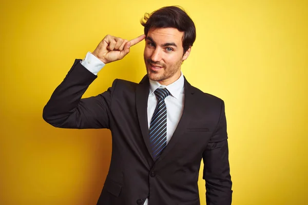 スーツとネクタイを着た若いハンサムなビジネスマンは 孤立した黄色の背景の上に立って 1本の指で頭を指差し 素晴らしいアイデアや思考 良い思い出 — ストック写真