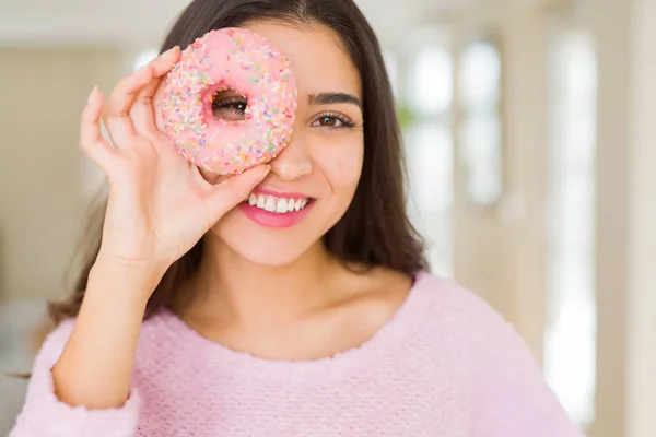 Belle jeune femme souriante regardant à travers beignet rose sur le — Photo