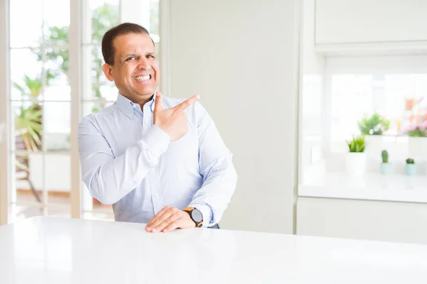 Mężczyzna Średnim Wieku Siedzi Domu Wesoły Uśmiechem Twarzy Wskazując Ręką — Zdjęcie stockowe