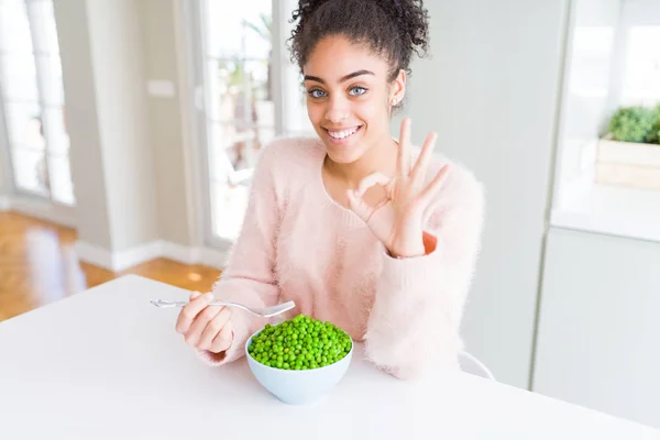 Young African American Girl Eating Healthy Green Peas Doing Sign — Stock Photo, Image