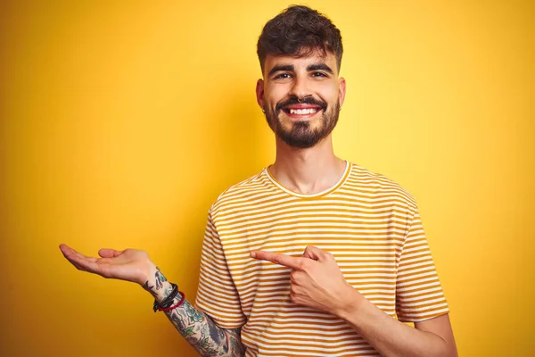Mladý Muž Tetováním Proužkované Košili Stojící Nad Izolovaným Žlutým Pozadím — Stock fotografie