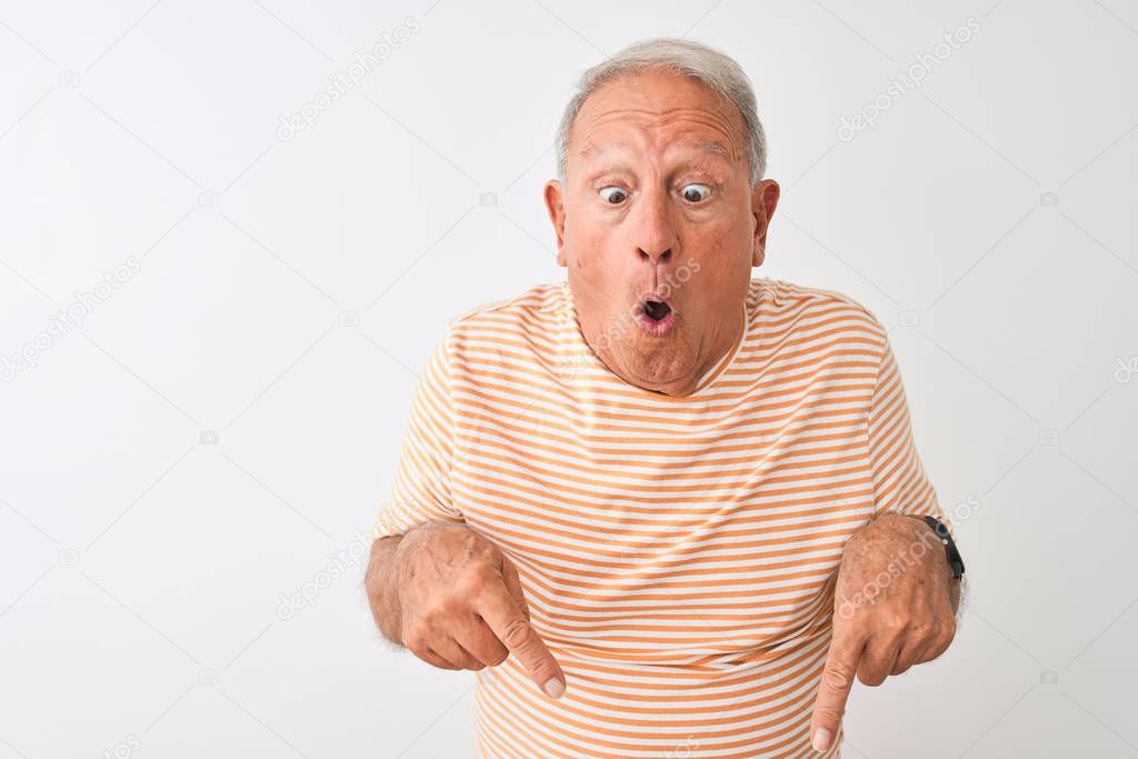 Senior grey-haired man wearing striped t-shirt standing over isolated white background Pointing down with fingers showing advertisement, surprised face and open mouth