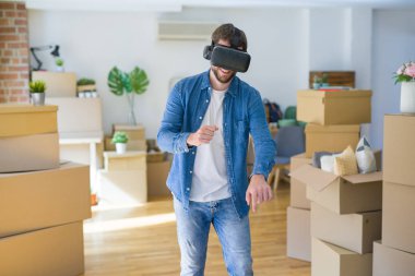 Yeni bir eve hareket karton kutular etrafında bir simülasyon oyunu oynarken sanal gerçeklik gözlük giyen genç adam