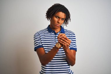 Çizgili mavi polo giyen dreadlocks giyen Afro adam izole beyaz arka plan üzerinde duran eller ve parmaklar acı ağrı, artrit iltihabı