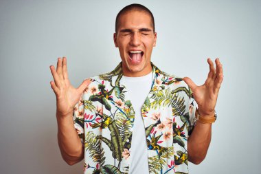 Genç yakışıklı adam tatilbeyaz arka plan üzerinde Hawaii gömlek giyen silah kaldırdı ve kapalı gözleri heyecanlı çığlık ile başarı için deli ve deli kutluyor. Kazanan kavramı