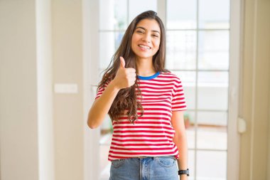 Genç güzel kadın hareketi el ile mutlu Yaşasın yaparken rahat t-shirt giyiyor. Başarı gösteren kameraya bakarak ifade onaylama.