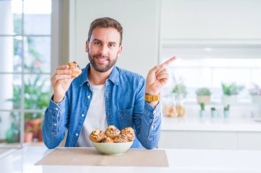 Yakışıklı adam çikolata cipsi muffin yeme çok mutlu yan el ve parmak ile işaret