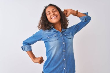 Genç Brezilyalı kadın geri uzanan izole beyaz arka plan üzerinde duran denim gömlek giyen, yorgun ve rahat, uykulu ve sabahın erken saatlerinde esneme