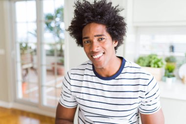 Afro-Amerikan adam yüzünde mutlu ve serin bir gülümseme ile çizgili t-shirt giyiyor. Şanslı kişi.