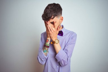Dövme mor gömlek ve papyon izole beyaz arka plan üzerinde giyen genç adam üzgün ifade ile elleri ile yüz kapsayan ağlarken. Depresyon kavramı.