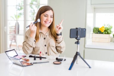 Güzel genç influencer kadın kayıt video öğretici çok mutlu yan el ve parmak ile işaret makyaj