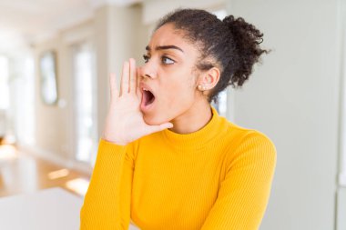 Bağırarak ve ağzı üzerinde el ile yan için çığlık afro saçlı güzel genç Afro-Amerikan kadın. İletişim kavramı.