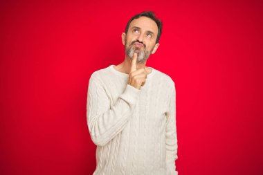 Izole kırmızı arka plan üzerinde gri saçlı Yakışıklı orta yaş yaşlı adam çene üzerinde parmak ile şüphe hakkında konsantre ve merak bakarak