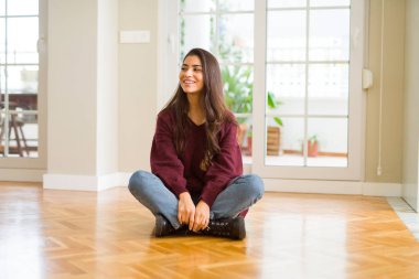 Ev uzak tarafına gülümseme ile yüzünde, doğal ifade arıyorum, yerde oturan genç güzel kadın. Kendine güvenen gülüyor.