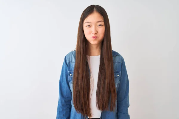 Молодая Китаянка Джинсовой Рубашке Стоит Изолированном Белом Фоне Пыхтя Щеками — стоковое фото