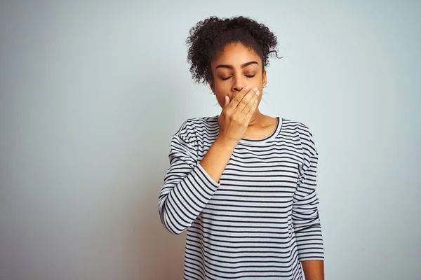 African american woman wearing navy striped t-shirt standing over isolated white background bored yawning tired covering mouth with hand. Restless and sleepiness.