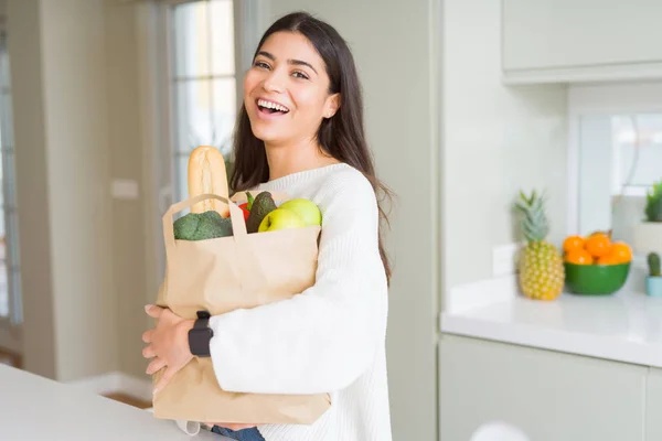 Schöne junge Frau lächelnd mit einer Papiertüte voller Lebensmittel — Stockfoto