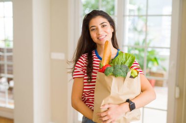 Güzel genç kadın gülümseyen tutan bir kağıt çanta dolu taze 