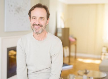 Evde kameraya bakarak gülümseyen yakışıklı orta yaş erkek