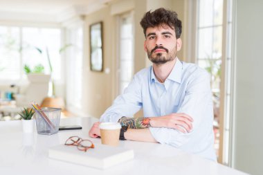 Genç iş adamı yüzünde ciddi ifade ile çalışıyor. Kameraya basit ve doğal bir bakış.