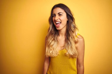 Genç güzel kadın sarı izole arka plan üzerinde t-shirt giyen kızgın ve deli çığlık sinirli ve öfkeli, öfke ile bağırarak. Öfke ve agresif kavram.