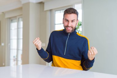 Yakışıklı adam evde geçirilen silahlarla şaşırmış ve başarı için hayran kutluyor ve gözleri açık. Kazanan kavramı.