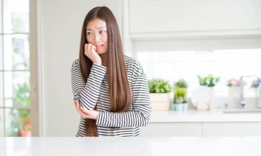 Güzel Asyalı kadın çizgili kazak giyen stresli ve sinirli ağız tırnakısırma elleri ile arıyorum. Anksiyete sorunu.