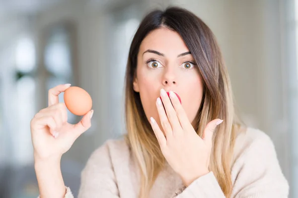 Young Beautiful Woman Holding Fresh Egg Home Cover Mouth Hand — Stock Photo, Image