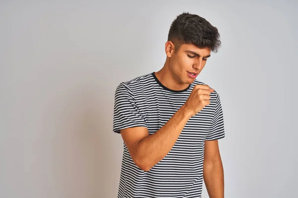 Young indian man wearing navy striped t-shirt standing over isolated white background feeling unwell and coughing as symptom for cold or bronchitis. Healthcare concept.