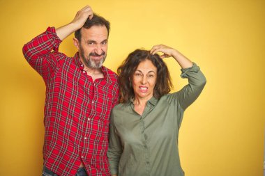 İzole sarı arka plan üzerinde güzel orta yaş çift karıştırır ve soru hakkında merak ediyorum. Şüphe ile belirsiz, baş el ile düşünme. Pensive kavramı.