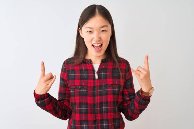 Izole beyaz arka plan üzerinde duran rahat ceket giyen genç Çinli kadın elleri yukarı ile rock sembolü yapıyor deli ifade ile bağırıyor. Müzik yıldızı. Ağır müzik konsepti.