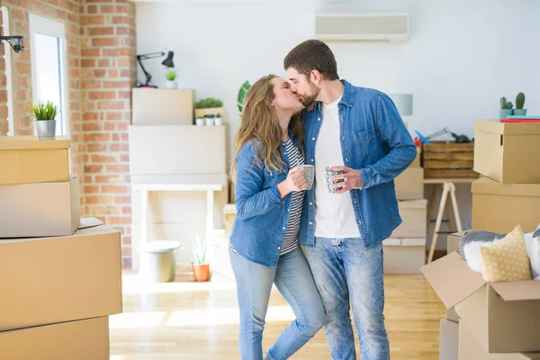 年轻夫妇从搬到新家放松 在纸板箱周围喝咖啡 — 图库照片