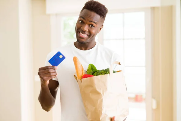 Hombre Afroamericano Sosteniendo Bolsa Papel Llena Comestibles Con Tarjeta Crédito — Foto de Stock