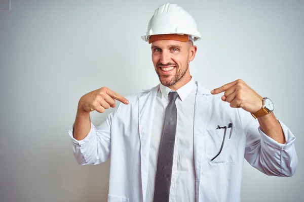年轻的英俊工程师男子戴着安全帽在孤立的背景看起来自信与微笑的脸 指着自己用手指骄傲和快乐 — 图库照片