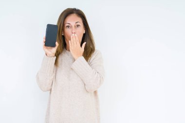 Orta yaş kadın hata için utanç ile şok el ile izole arka plan kapağı ağız üzerinde akıllı telefon ekranı gösteren, korku ifadesi, sessizlik, gizli kavram korkmuş