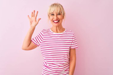 Orta yaş kadın çizgili t-shirt izole pembe arka plan üzerinde duran giyen gösteren ve parmakları ile işaret ederken emin ve mutlu gülümseyerek beş.
