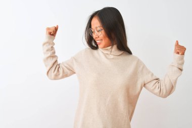 Genç çinli kadın boğazlı kazak ve gözlük giyen izole beyaz arka plan üzerinde kol kasları gururla gülümseyen gösteren. Fitness konsepti.