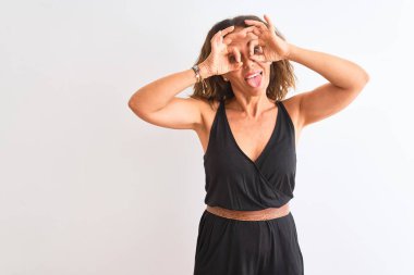 Siyah rahat elbise giyen orta yaşlı kadın izole beyaz arka plan üzerinde duran dürbün dil dışarı yapışması gibi ok jest yapıyor, gözleri parmaklardan bakarak. Çılgın ifade.