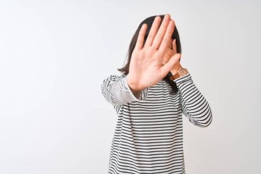 Genç güzel Çinli kadın çizgili t-shirt elleri ile gözleri kaplayan izole beyaz arka plan üzerinde duran ve üzgün ve korku ifadesi ile stop jest yapıyor giyiyor. Utanmış ve olumsuz kavram.