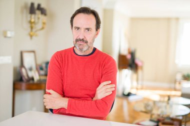 Evde yakışıklı orta yaş adam şüpheci ve sinir, kesişen silah ile yüz üzerinde ifade onaylamaz. Negatif kişi.