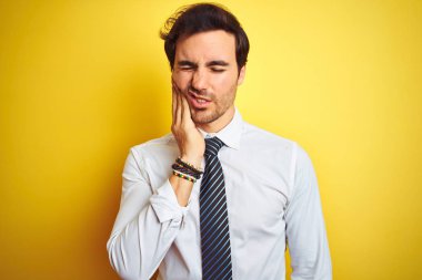 Genç yakışıklı işadamı zarif gömlek giyen ve izole sarı arka plan üzerinde kravat diş ağrısı veya diş üzerinde diş hastalığı nedeniyle ağrılı ifade ile el ile ağız dokunmadan. Diş hekimi konsepti.