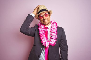 Takım elbise şapka gözlük takan genç işadamı hawaiian lei izole pembe arka plan üzerinde el ile baş stresli, utanç ve sürpriz yüz ile şok, kızgın ve sinirli. Korku ve hata için üzgün.