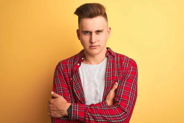 Genç yakışıklı adam izole sarı arka plan şüpheci ve sinirli üzerinde duran rahat gömlek giyen, çapraz kolları ile yüzünde ifade onaylamayan. Negatif kişi.