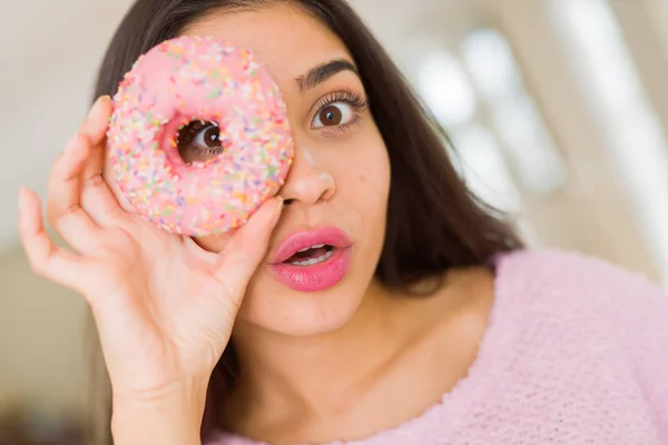 Beautiful young woman looking through pink donut on the eye with — Stock Photo, Image