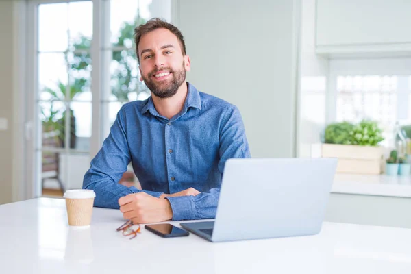 Hombre de negocios guapo trabajando con computadora portátil y sonriendo — Foto de Stock